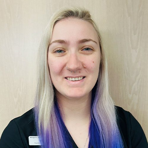 smiling female veterinary technician standing in front of wood panel wall
