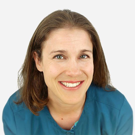 smiling female veterinarian wearing blue scrubs