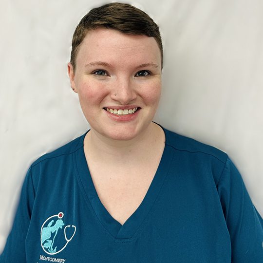 Evie wearing blue scrubs and smiling